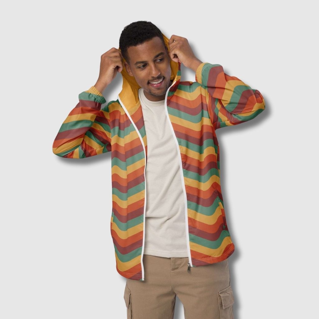 A man wearing a retro style windbreaker jacket with orange, red and yellow wavy stripes print.